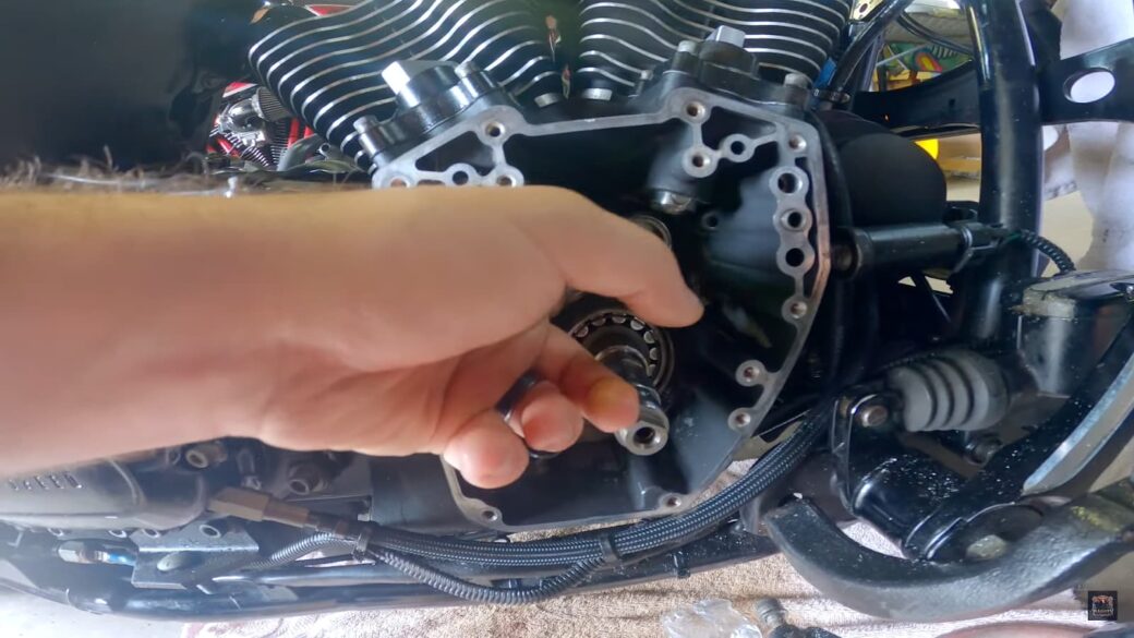 hand is captured mid-adjustment, working on the intricate parts of a motorcycle engine